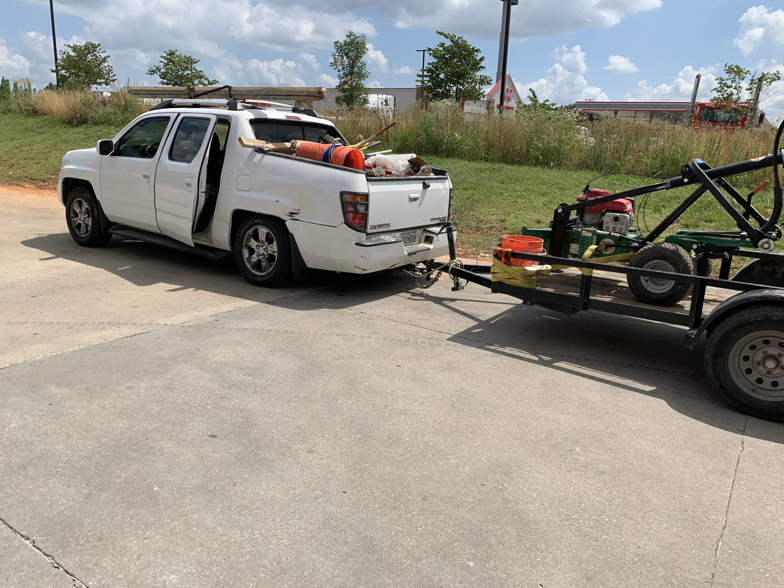 An early white work truck towing a small equipment trailer