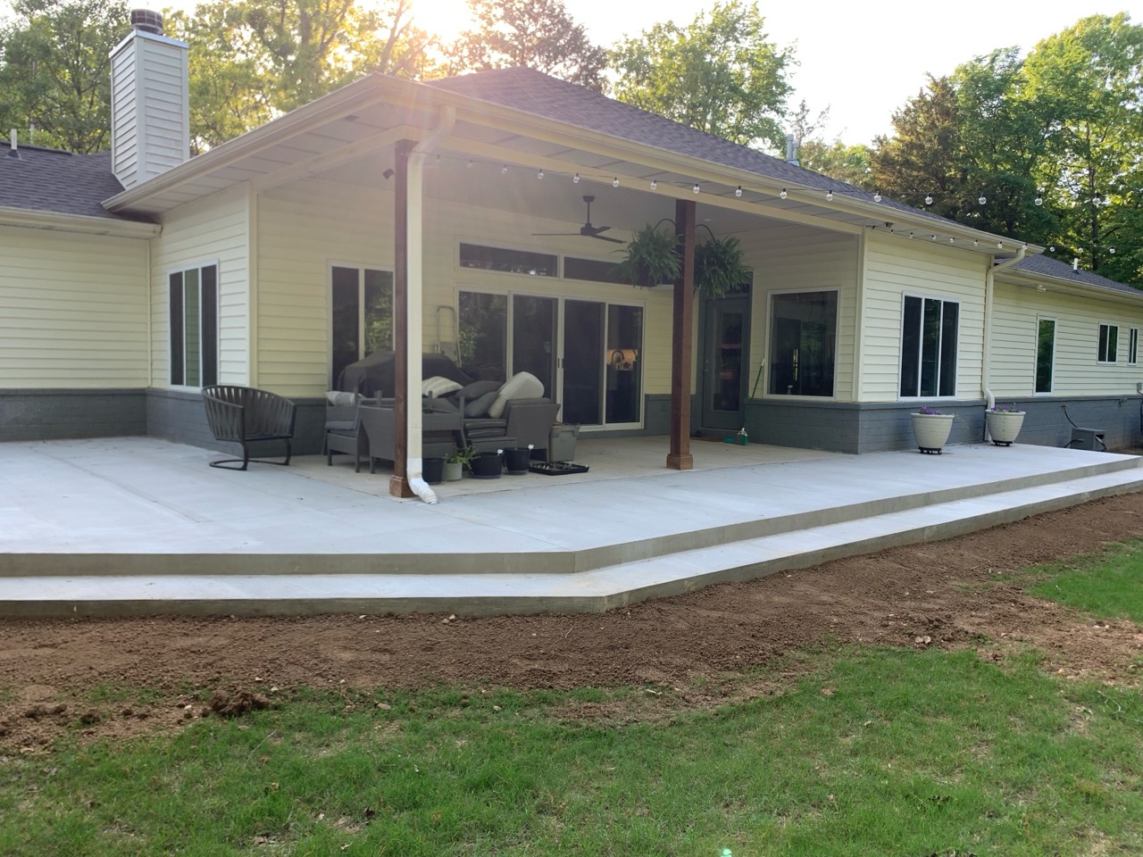 A large finished plain concrete patio wrapping around a covered outdoor space